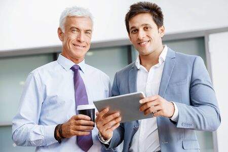 Two businessman in office with devicesの写真素材
