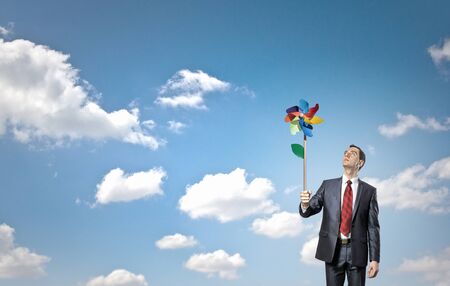 Young happy businessman with colorful windmill in handの写真素材
