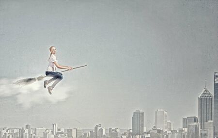 Happy young woman flying in sky on broomの写真素材