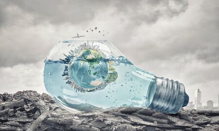 Glass light bulb filled with water and floating Earth planet.の写真素材
