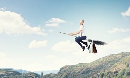 Happy young woman flying in sky on broomの写真素材