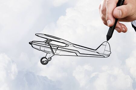 Person hand drawing old airplane on sky backgroundの写真素材