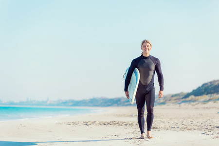 A young surfer with his board on the beachの写真素材