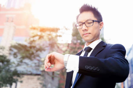 Businessman standing in street and looking at his watchの写真素材