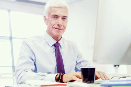 Businessman sitting in office working with computerの写真素材