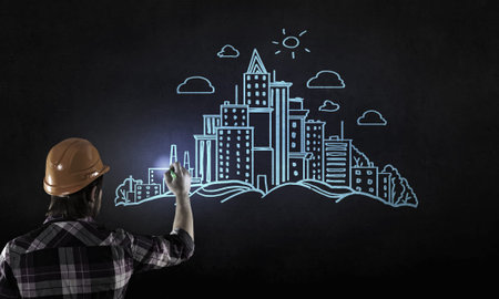 Back view of man engineer drawing building sketches on wallの写真素材