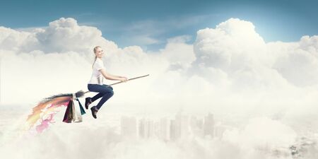 Happy young woman flying in sky on broomの写真素材