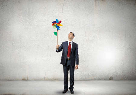 Young happy businessman with colorful windmill in handの写真素材