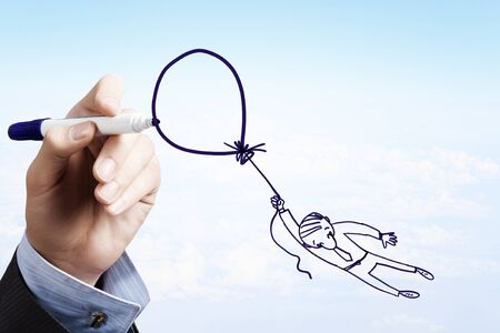 Man hand drawing caricature of businessman flying on balloonの写真素材