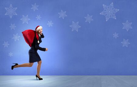 Santa woman running with red gift bag on backの写真素材