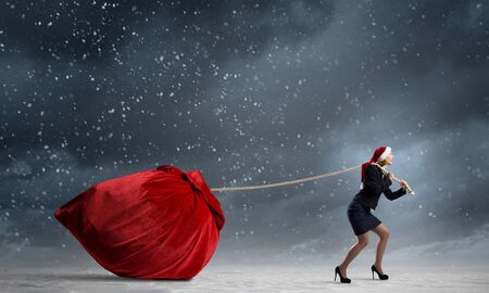 Santa woman pulling huge red gifts bagの写真素材