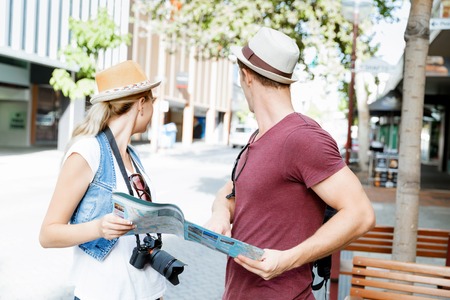 Happy young couple as tourists with a mapの写真素材