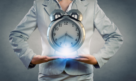 Close up of businesswoman holding in hands alarm clockの写真素材