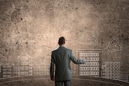 Back view of businessman drawing sketches of construction project on wallの写真素材