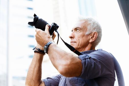 Senior man with camera in cityの写真素材