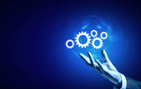 Businessperson hand holding gears and cogwheels in palmの写真素材