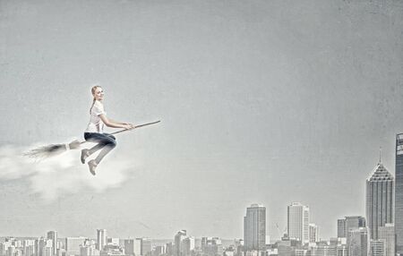 Happy young woman flying in sky on broomの写真素材