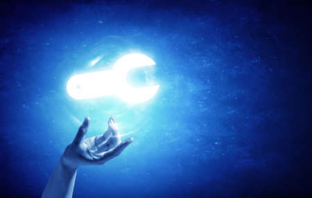 Person hand taking glowing tool sign on blue backgroundの写真素材