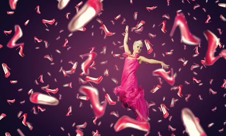 Young cheerful woman in dress and many falling shoesの写真素材
