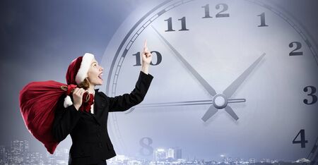 Santa woman with red bag on back pointing up with fingerの写真素材