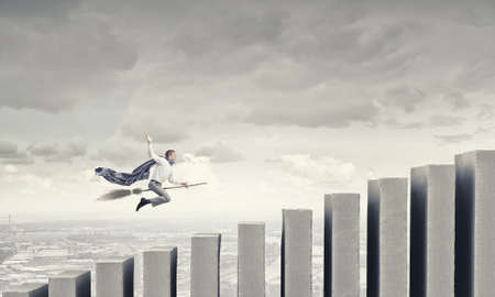 Young businessman flying on broom and growth conceptの写真素材