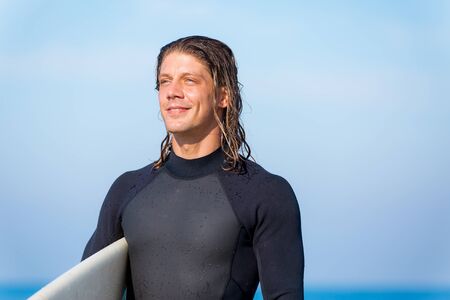 A young surfer with his board on the beachの写真素材