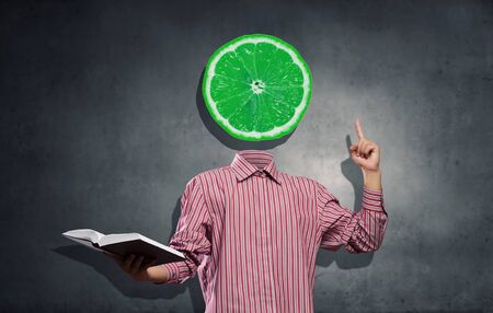 Headless man with book in hand anf lemon instead of headの写真素材