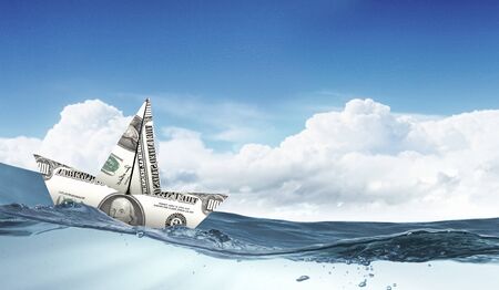 Ship made of dollar banknote floating in waterの写真素材