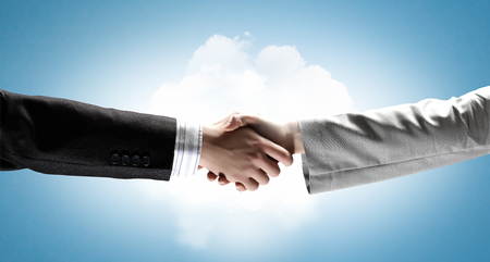 Close up of business handshake on digital backgroundの写真素材