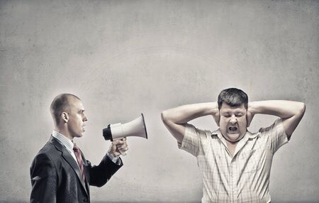 Furious man screaming agressively in megaphone at manの写真素材