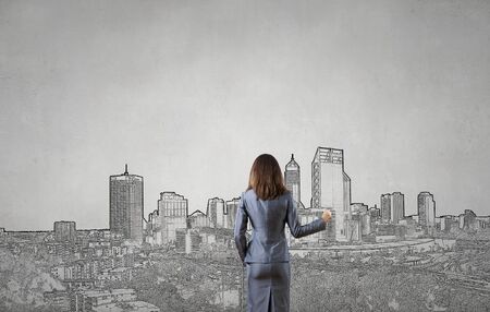 Back view of businesswoman drawing sketches of construction project on wallの写真素材