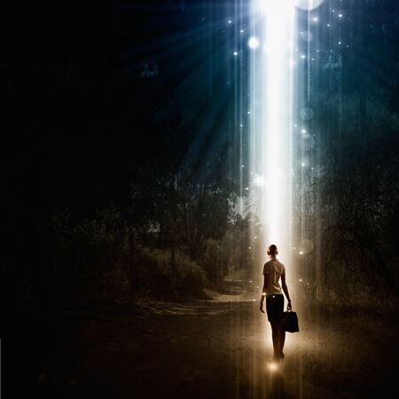 Rear view of businesswoman standing in light going from above