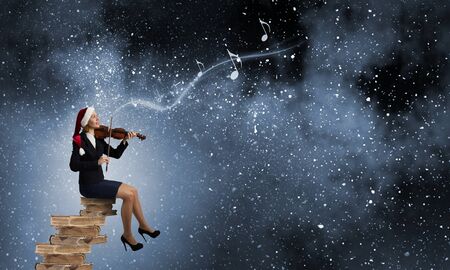 Woman in formal suit and Santa hat playing violinの写真素材