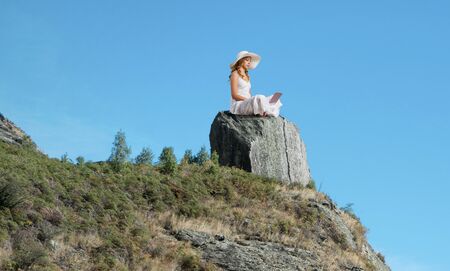 Young lady sitting on top of mountain with laptopの写真素材
