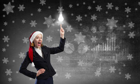 Santa woman pointing on light bulb with fingerの写真素材