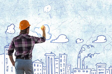 Back view of man engineer drawing building sketches on wall