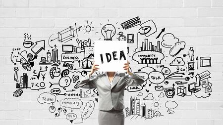 Unrecognizable businesswoman holding paper covering her faceの写真素材