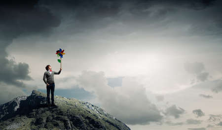 Young happy guy in casual with colorful windmill in handの写真素材