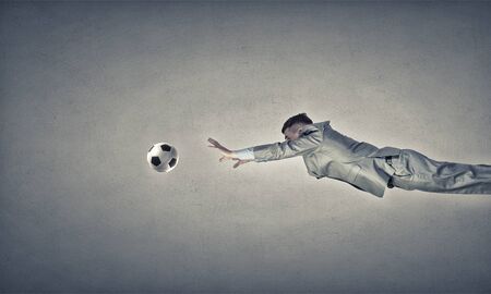 Businessman in suit jumping to hit soccer ballの写真素材