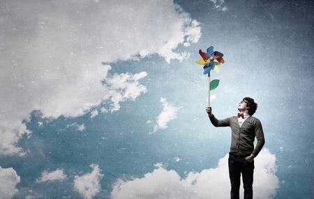 Young happy guy in casual with colorful windmill in handの写真素材