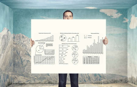 Businessman holding banner with graphs and diagrams conceptの写真素材