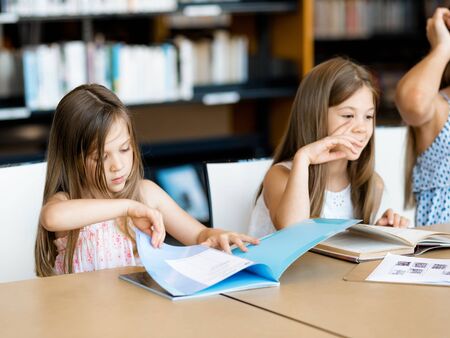 Little girls reading books in libraryの写真素材