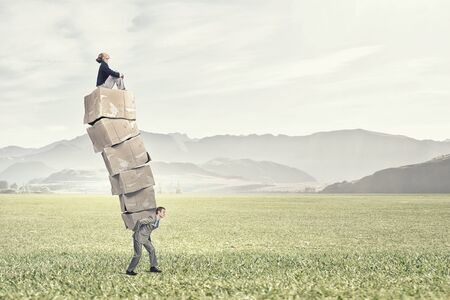 Businessman carrying big stack of carton boxesの写真素材