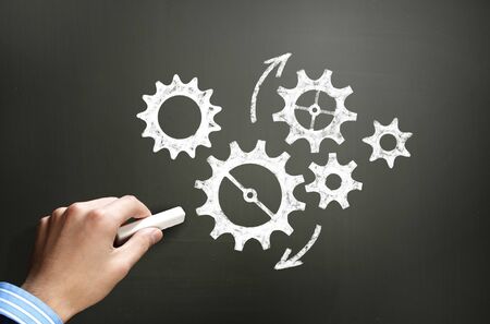 Businessman hand drawing with chalk gears mechanism as teamwork conceptの写真素材
