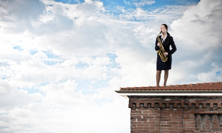 Young woman in suit with saxophone in handsの写真素材