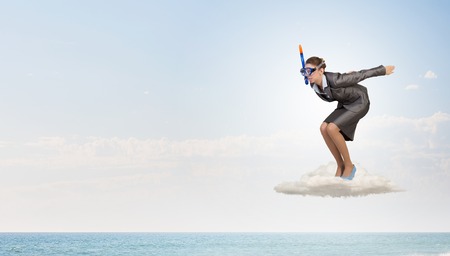 Young businesswoman in suit and diving mask jumping in waterの写真素材