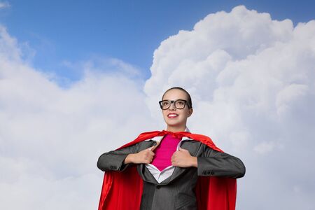 Businesswoman wearing red cape and opening her shirt like superheroの写真素材