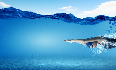 Young woman swimmer in cap and glasses under water