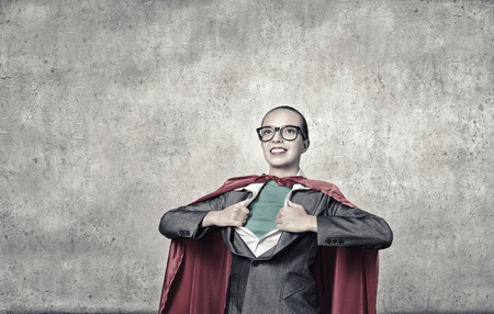 Businesswoman wearing red cape and opening her shirt like superheroの写真素材