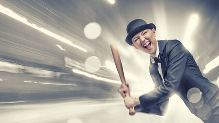 Young emotional woman in suit and hat with baseball batの写真素材